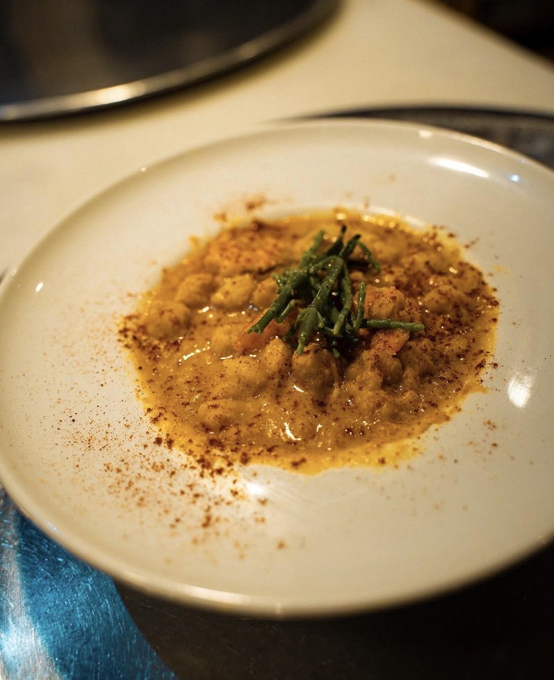 Plato hondo con un guiso especiado y hierbas frescas por encima